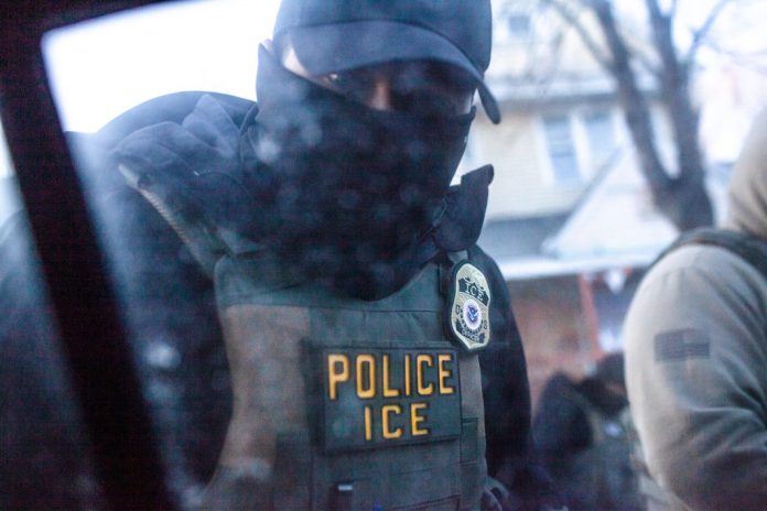 A masked U.S. Immigration and Customs Enforcement agent knocks on a car window in Minnesota on Jan. 12, 2026. (Photo by Nicole Neri/Minnesota Reformer)