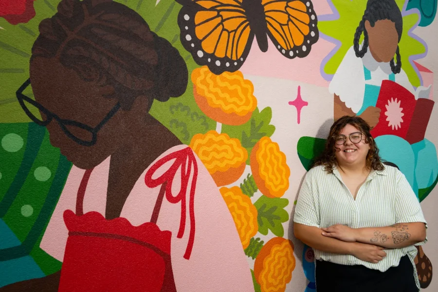 La muralista Marissa Hernandez posa frente a su obra en Nos Books, en Des Moines