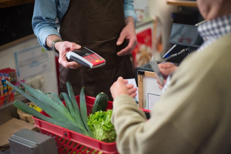 A shopper pays for groceries with a card; image illustrating Illinois’ $400 FRESH payment.