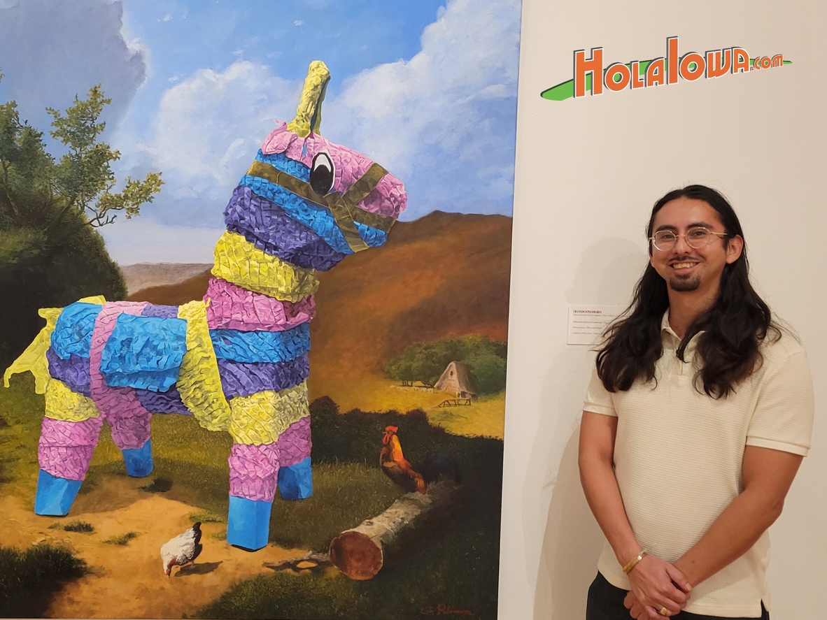 Artist Francisco Palomares stands in front of his painting Piñata and chickens in a landscape at the Des Moines Art Center.